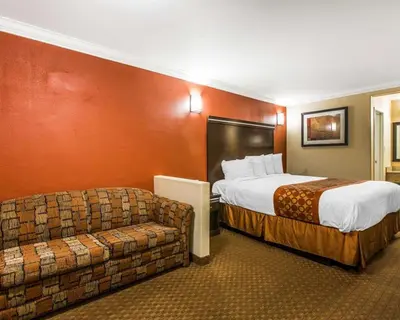 a hotel room with a bed and a couch at Rodeway Inn & Suites Corona in Corona