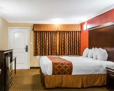 a hotel room with a bed and a television at Rodeway Inn & Suites Corona in Corona