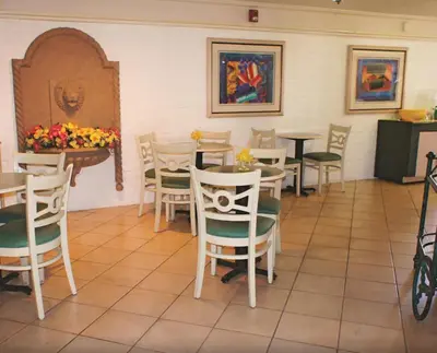 a dining room with tables and chairs and flowers at La Quinta Inn by Wyndham Bakersfield South in Bakersfield