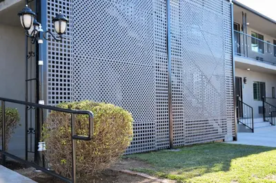 a fence with a bush in front of a building at Tilbury Inn in Glendale