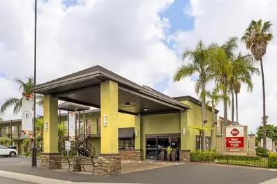 a yellow building with palm trees in front of it at Best Western Plus Pavilions in Anaheim