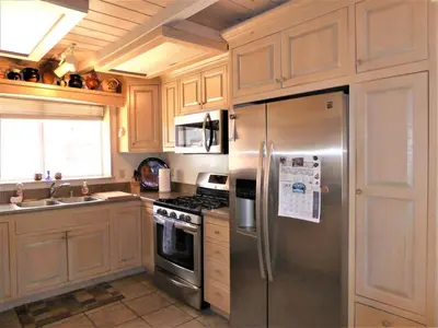 a kitchen with a stainless steel refrigerator and a sink at Dream Getaway-Secluded Hot Spa-Walk to Village-Walk to Pineknot Trailhead-Plus King Bed! in Big Bear Lake
