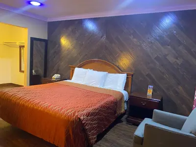 a hotel room with a bed and a chair at Villa Park Motel in Orange