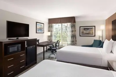 a hotel room with two beds and a flat screen tv at La Quinta by Wyndham Bakersfield North in Bakersfield
