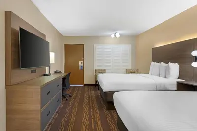 a hotel room with two beds and a flat screen tv at Best Western Plus Stovall's Inn in Anaheim