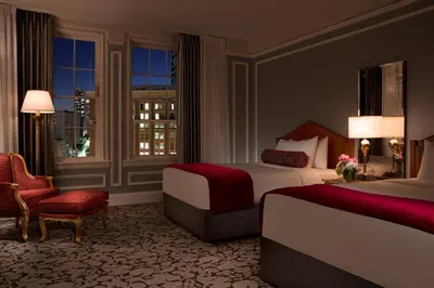 a hotel room with two beds and a chair at The Biltmore Los Angeles in Los Angeles