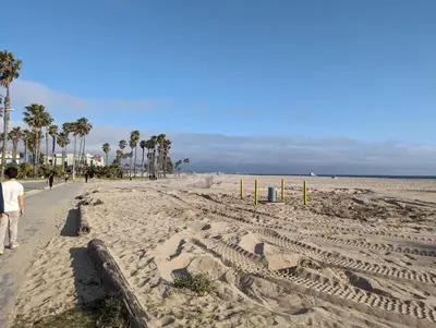 a beach with palm trees and people walking on it at 2Bedroom with Den and 2BA 4 Blocks to Santa Monica Beach in Los Angeles