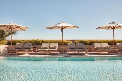 a group of chairs and umbrellas next to a swimming pool at Santa Monica Proper Hotel, a Member of Design Hotels in Los Angeles