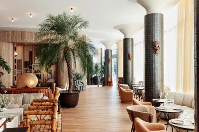 a lobby with tables and chairs and palm trees at Santa Monica Proper Hotel, a Member of Design Hotels in Los Angeles