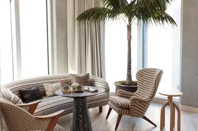 a living room with a couch and two chairs and a palm tree at Santa Monica Proper Hotel, a Member of Design Hotels in Los Angeles