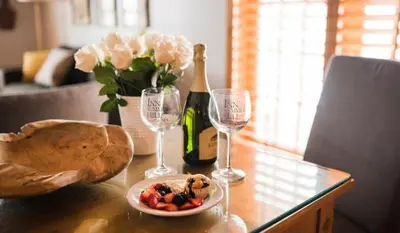 a table with a bottle of wine and two wine glasses at Inn On SummerHill in Summerland