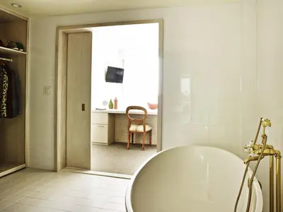 a white bathroom with a tub and a chair at The LINE Hotel LA in Los Angeles