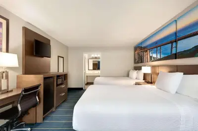 a hotel room with two beds and a desk at Days Inn & Suites by Wyndham Anaheim At Disneyland Park in Anaheim