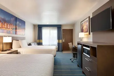 a hotel room with two beds and a flat screen tv at Days Inn & Suites by Wyndham Anaheim At Disneyland Park in Anaheim
