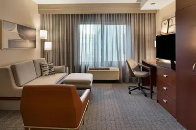 a living room with a couch and a desk in a hotel room at Courtyard Long Beach Airport in Long Beach
