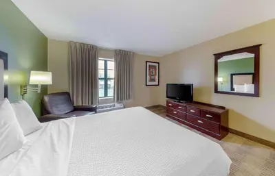 a hotel room with a bed and a mirror and a chair at Extended Stay America Suites - Orange County - Huntington Beach in Huntington Beach