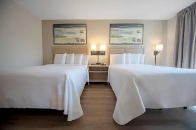 two beds in a hotel room with white sheets at Extended Stay America Suites - Orange County - Anaheim Convention Center in Anaheim
