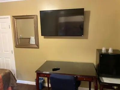 a room with a table and a television on the wall at SunLight Motel Long Beach in Long Beach
