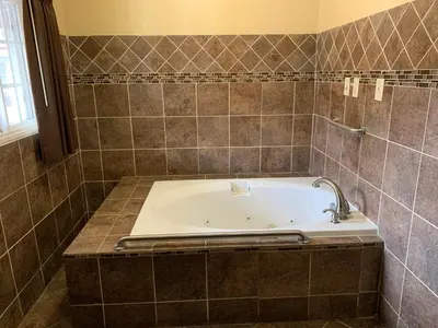 a bath tub in a tiled bathroom with a sink at SunLight Motel Long Beach in Long Beach
