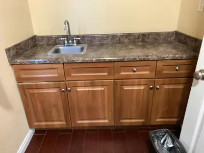 a kitchen with a sink and wooden cabinets at SunLight Motel Long Beach in Long Beach