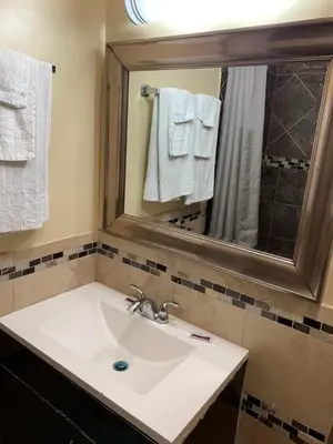 a bathroom with a sink and a mirror and towels at SunLight Motel Long Beach in Long Beach