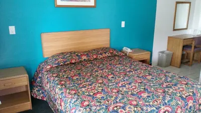 a bedroom with a bed and a blue wall at Economy Inn Motel in Sylmar