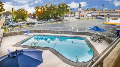 a swimming pool with umbrellas and a parking lot at Sea Rock Inn - Long Beach in Long Beach