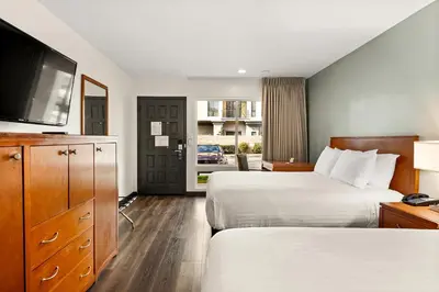 a hotel room with two beds and a flat screen tv at Vagabond Inn Glendale in Glendale