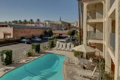 a view of a swimming pool with chairs and an umbrella at Vagabond Inn Glendale in Glendale