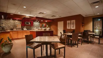 a restaurant with tables and chairs and a kitchen at Hotel d'Lins Ontario Airport in Ontario
