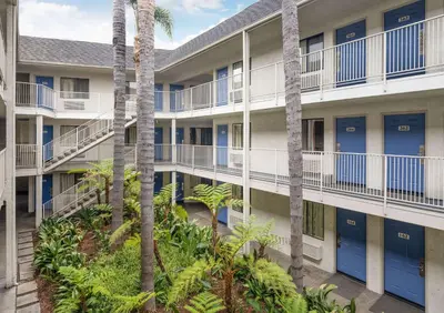 an apartment building with blue doors and palm trees at Motel 6-Buena Park, CA - Knotts Berry Farm - Disneyland in Buena Park
