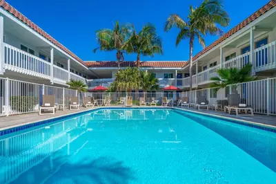 a swimming pool in front of a hotel with palm trees at Motel 6-Carpinteria, CA - Santa Barbara - South in Carpinteria