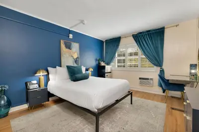 a blue bedroom with a bed and a television at Magic Castle Hotel in Los Angeles