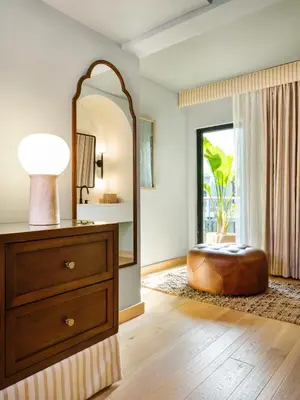 a bedroom with a mirror and a ottoman in front of a window at Palihotel Hollywood near Universal Studios in Los Angeles