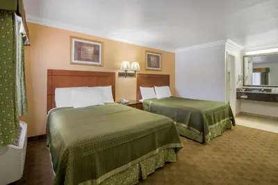 a hotel room with two beds with green sheets at Rodeway Inn Adelanto US 395 in Adelanto