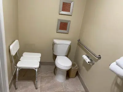 a bathroom with a white toilet and a chair at Quality Inn Downey in Downey