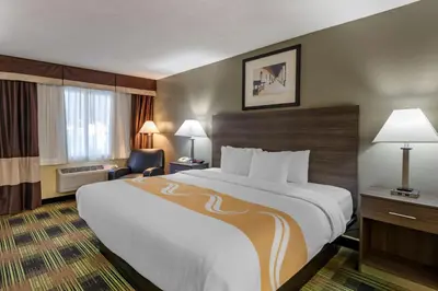 a hotel room with a large bed and a chair at Quality Inn Barstow Route 66 in Barstow