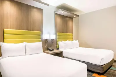 two beds in a hotel room with white and yellow at Rodeway Inn near Melrose Ave in Los Angeles