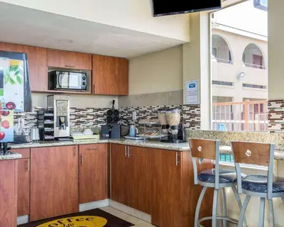 a kitchen with wooden cabinets and a counter with stools at Rodeway Inn Delano in Delano