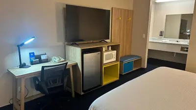 a hotel room with a bed and a desk with a television at Days Inn by Wyndham Ridgecrest near China Lake Naval Station in Ridgecrest