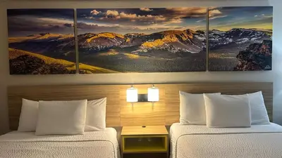 two beds in a hotel room with snow capped mountains at Days Inn by Wyndham Ridgecrest near China Lake Naval Station in Ridgecrest