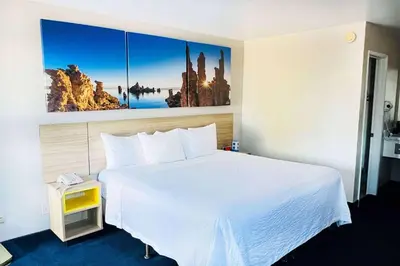 a hotel room with a white bed and a painting on the wall at Days Inn by Wyndham Ridgecrest near China Lake Naval Station in Ridgecrest