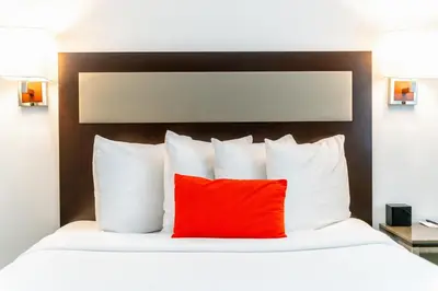 a bed with a red pillow in a hotel room at Inn at 50 Long Beach Convention Center in Long Beach