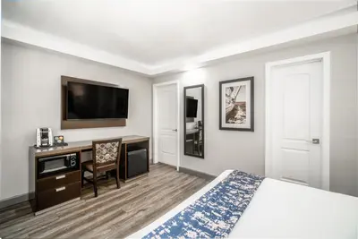 a hotel room with a bed and a desk and a tv at Inn at 50 Long Beach Convention Center in Long Beach