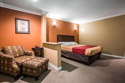 a hotel room with a bed and a chair at Baymont by Wyndham Ontario in Ontario