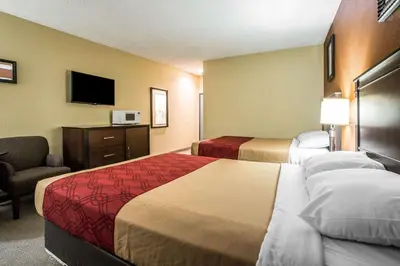 a hotel room with two beds and a chair and a television at Baymont by Wyndham Ontario in Ontario