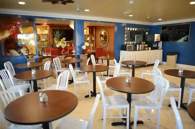 a restaurant with wooden tables and white chairs at Hotel Le Reve Pasadena in Pasadena