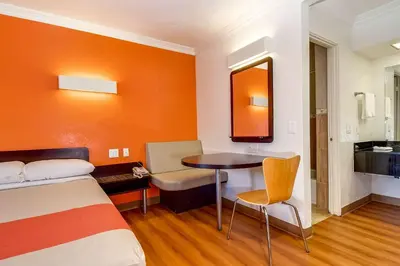a hotel room with a bed and a table and a mirror at Motel 6 Garden Grove in Anaheim