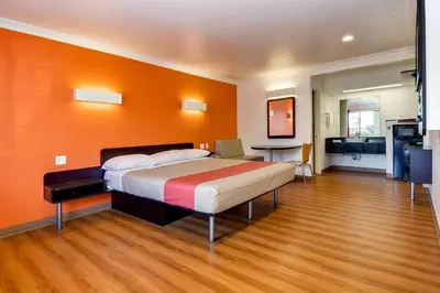 a bedroom with a bed with an orange wall at Motel 6 Garden Grove in Anaheim