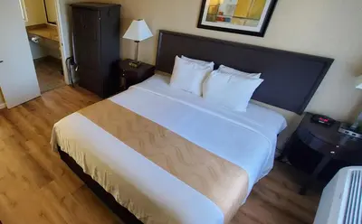 a bedroom with a large bed with white sheets and pillows at Quality Inn & Suites Anaheim at the Park in Anaheim